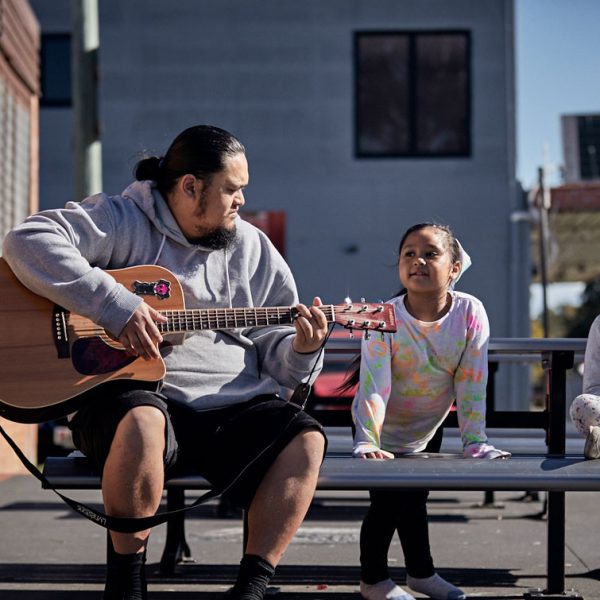 Person playing the guitar to a child