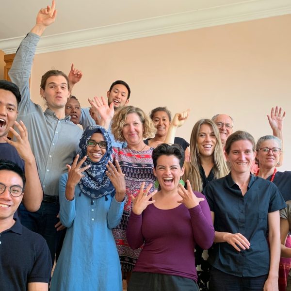 A group of people standing on the staircase smiled with their hands in the air.
