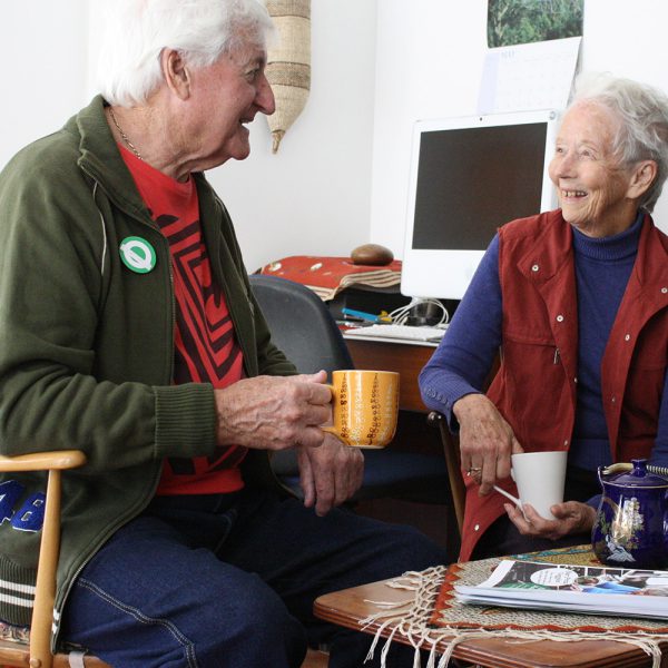 Two elderly people sitting and talking over a cup of tea