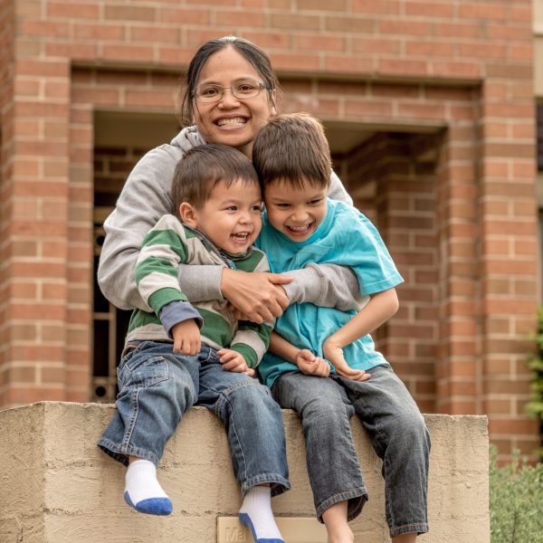 Mother standing outside her house hugging her children