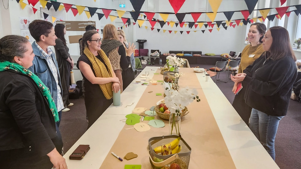 Photo of people gathered around a table standing and talking