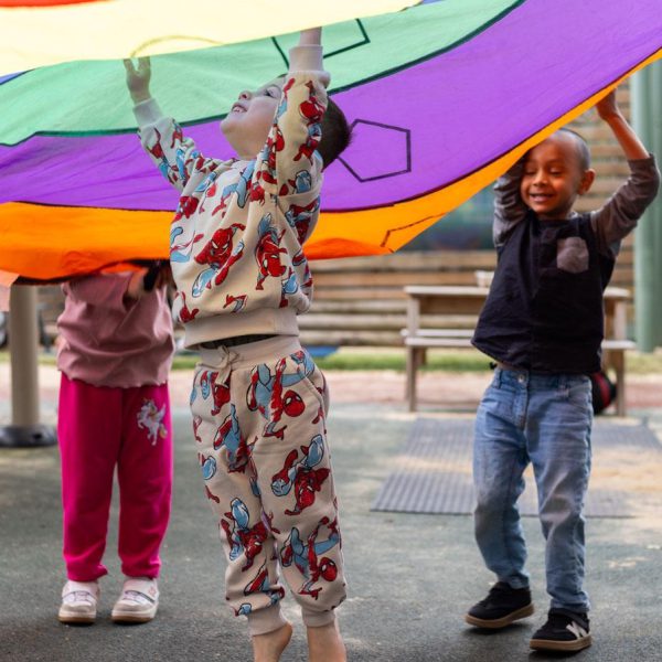Children playing under a colourful parachute