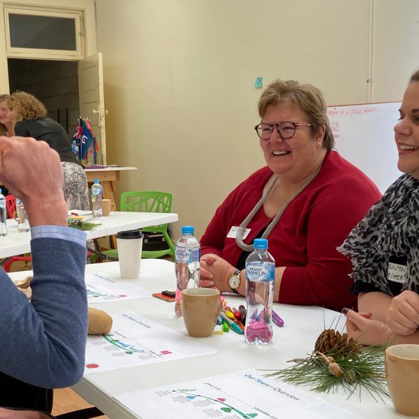 A man talking over a table to two women at an Our Town workshop