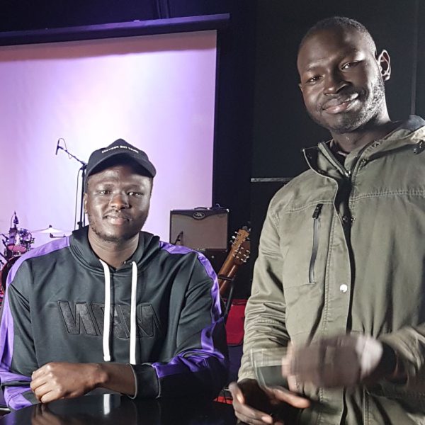 Two South Sudanese Australians standing in front of a stage