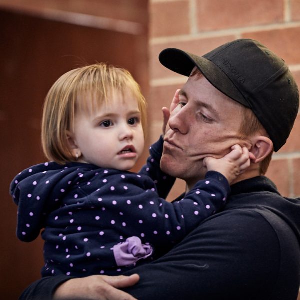 Father holding daughter while she plays with his cheeks